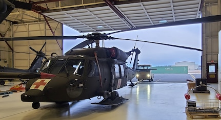 An Alaska Army National Guard HH-60M Black Hawk medical evacuation helicopter is pulled out of hangar six at Bryan Army Airfield on Joint Base Elmendorf-Richardson as part of a routine training mission March 26, 2025. Soldiers with G Company, 2-211th General Support Aviation Battalion, rescued three people from the wreckage of a crashed PA-12 Super Cruiser partially submerged in glacial ice March 24, 2025.