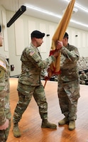 A senior Army leaders hand off the unit flag to another senior Army leader.