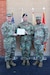 Three senior Army leaders stand together, the two on the left holding an award.