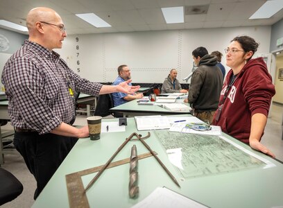Robert Nance, trade instructor, Shop 11, Shipfitters, talks with Jenean Valencia, electroplater helper, Shop 31, Inside Machinist, March 19, 2025, during the Apprentice Program Knowledge Fair at Puget Sound Naval Shipyard & Intermediate Maintenance Facility in Bremerton, Washington. (U.S. Navy photo by Wendy Hallmark)
