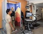Ancillary Services Chief and Physical Therapist, Lieutenant Commander Courtney Jones, takes Womack Army Medical Center Commander Col. Stephanie Mont through a posturography test which is useful to detect equilibrium and vestibular issues after concussion and helps the therapist and patient to set goals to return to duty during the Intrepid Spirit Center open house, March 7, 2025, Fort Bragg, North Carolina.