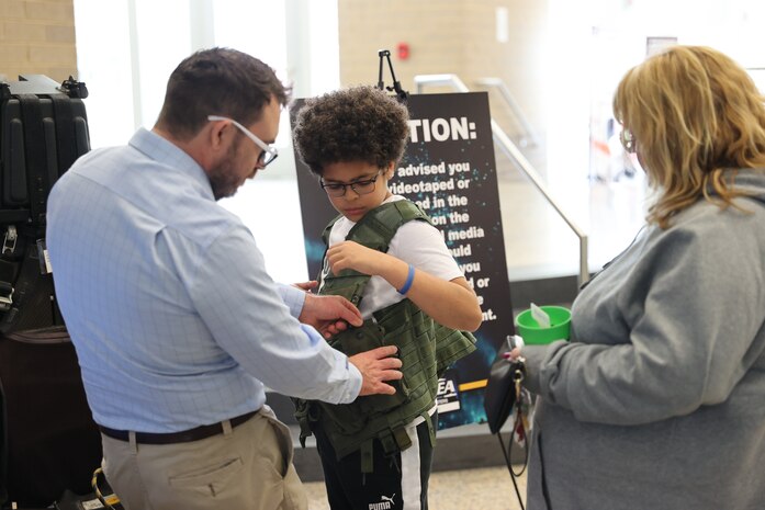 Josh Phillips, Naval Surface Warfare Center Indian Head Division’s public affairs officer, assists a student in securing a flight vest during the HITS Expo at Saint Charles High School in Waldorf, Maryland, March 22. (U.S. Navy photo by Staff Sgt. Arthur Jones/released)