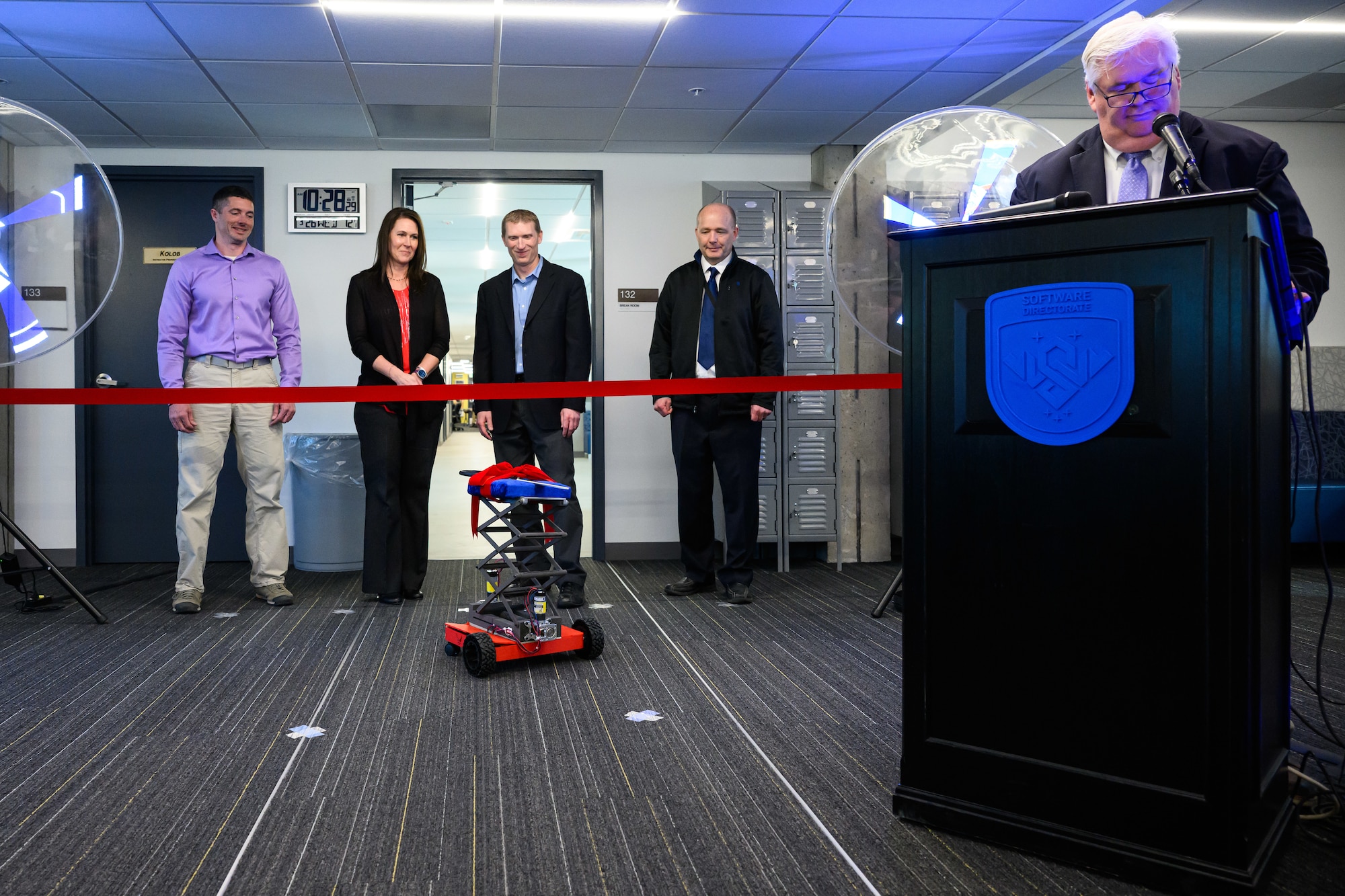 A robot proffers the ceremonial scissors during a 309th Software Engineering Group ribbon cutting ceremony for two new software training and onboarding facilities at Hill Air Force Base, Utah, March 26, 2025. The Launch Pad facility will help new hires awaiting security clearances enhance their skills and leadership, while SWEG U will provide ongoing training for 309th SWEG employees and software engineering groups from other bases. (U.S. Air Force photo by R. Nial Bradshaw)