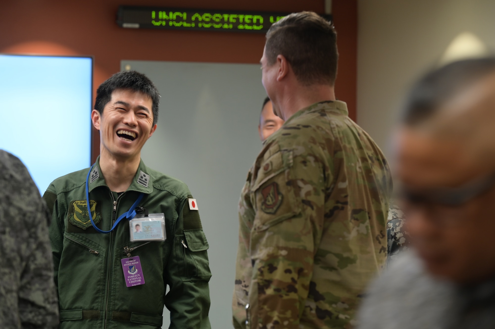 Japan Air Self-Defense Force laughs while speaking to a U.S. Air Force Airman.
