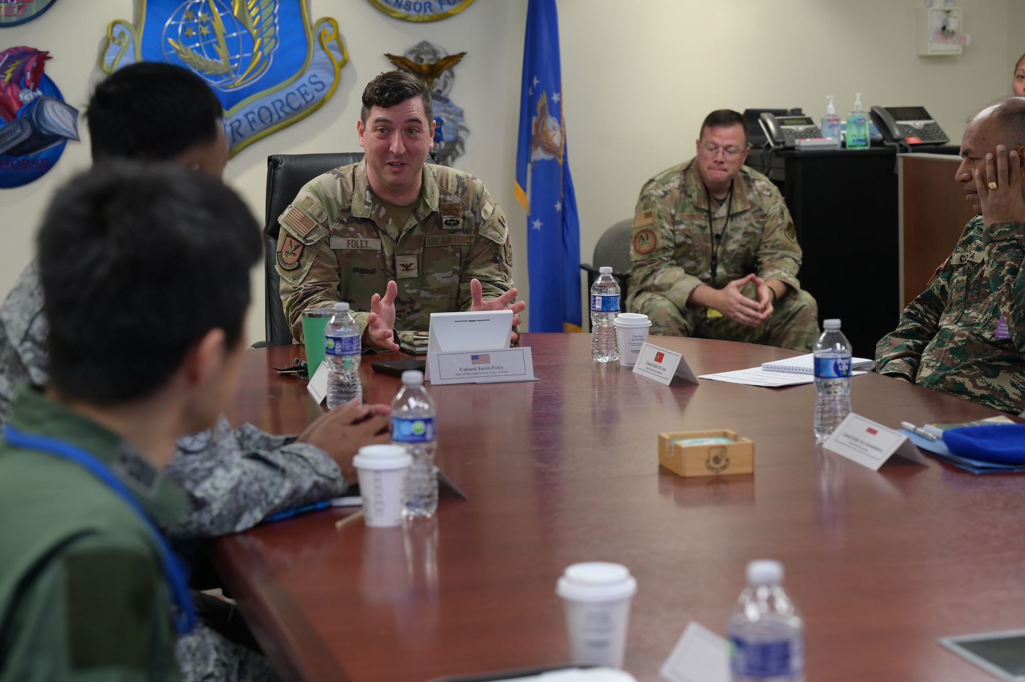 A U.S. Air Force Airman speaks at a table during a meeting with foreign visitors.