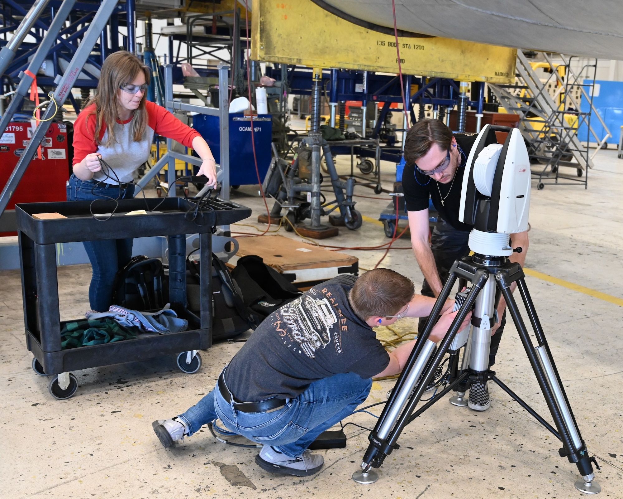 A woman and 2 men setting up a scanning tool.