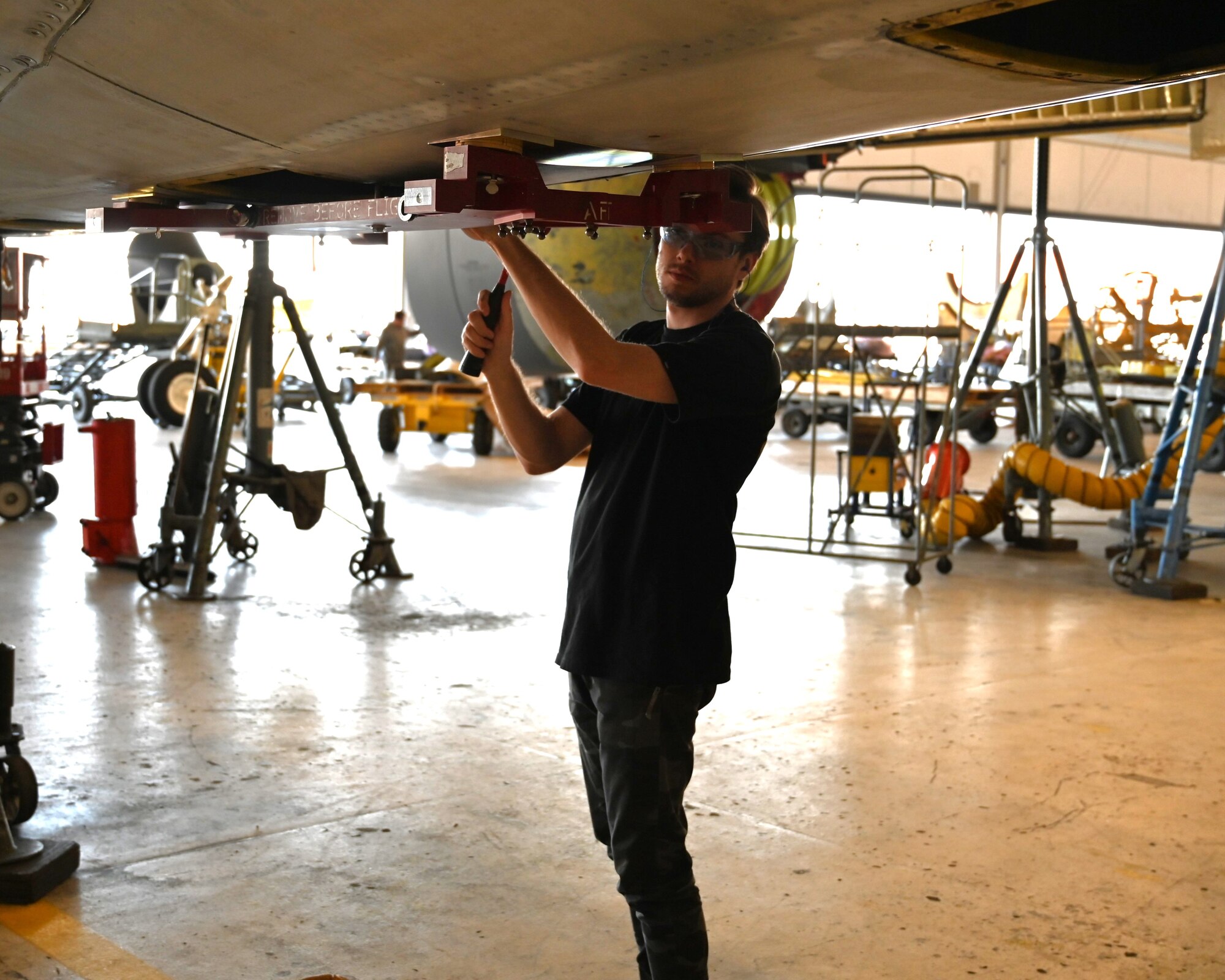 A man attaching a equipment to the bottom of a plane