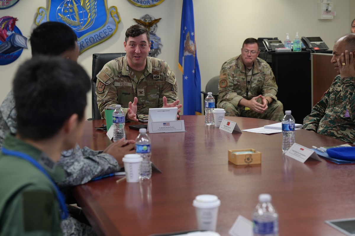 A U.S. Air Force Airman speaks at a table during a meeting with foreign visitors.