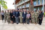 Secretary of Defense Pete Hegseth stands for a photo outdoors with more than 20 troops and civilians.