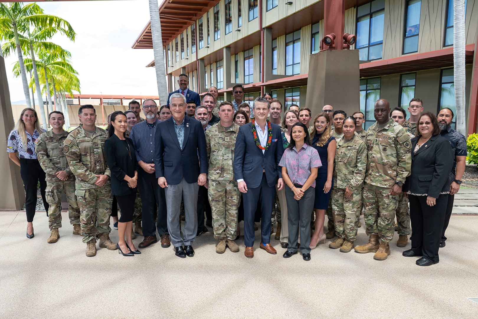 Secretary of Defense Pete Hegseth stands for a photo outdoors with more than 20 troops and civilians.