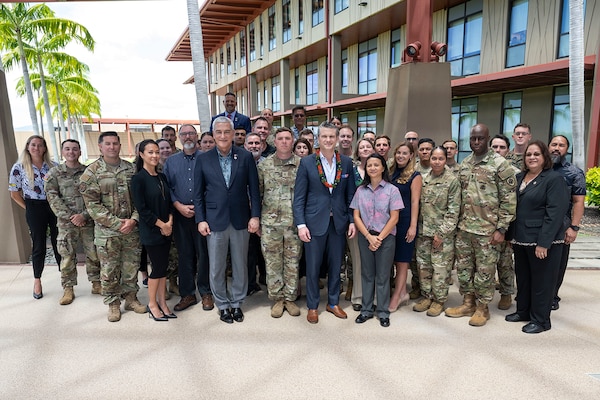 Secretary of Defense Pete Hegseth stands for a photo outdoors with more than 20 troops and civilians.