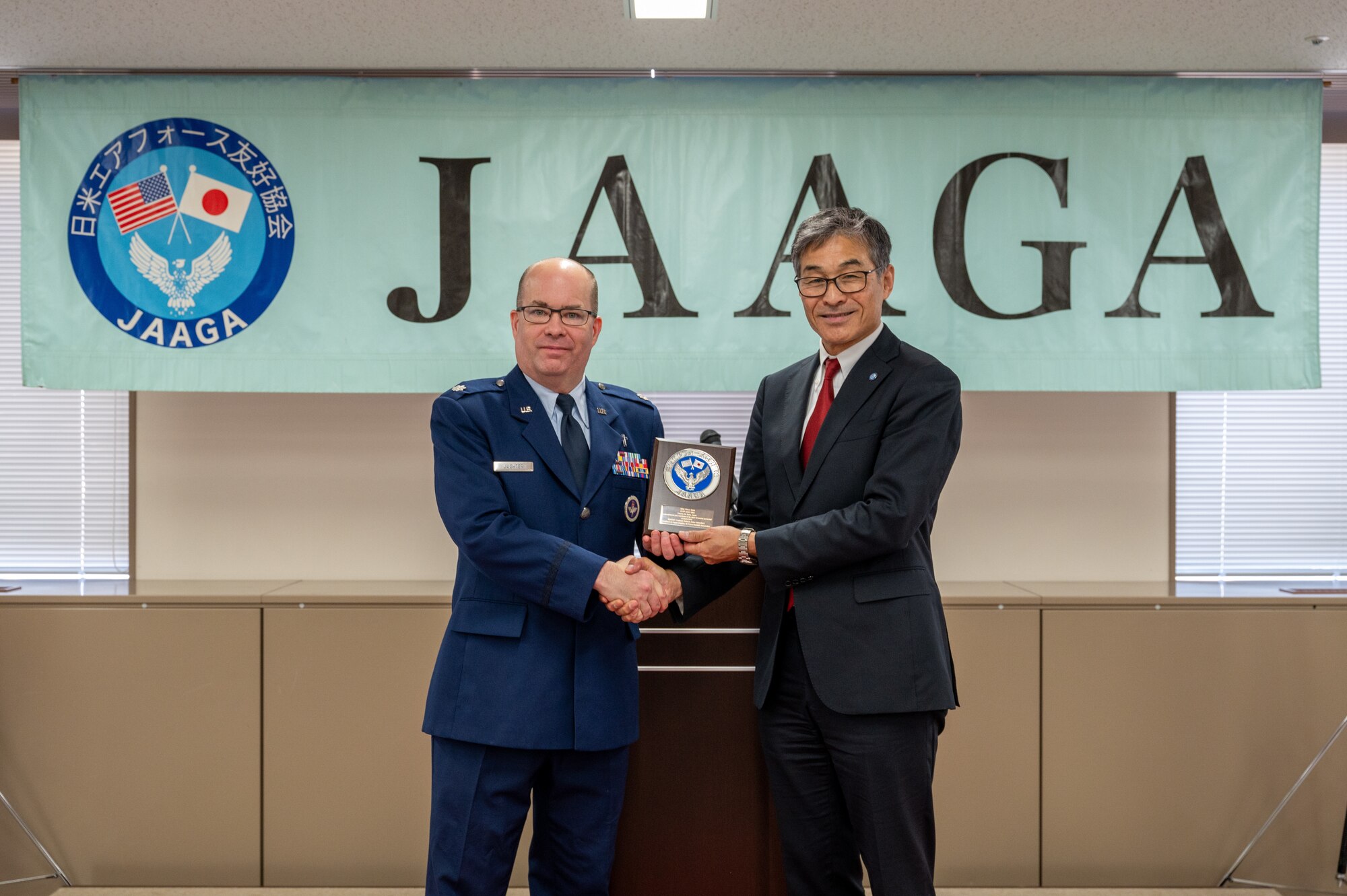 U.S. Air Force Lt. Col. Mark Juchter, 374th Airlift Wing chaplain, accepts an award from Yoshinari Marumo, president of the Japan-America Air Force Goodwill Association, on behalf of U.S. Air Force Staff Sgt. Dhruv Singh, 374 AW NCOIC of chapel operations, during the JAAGA Award Ceremony at Yokota Air Base, Japan.