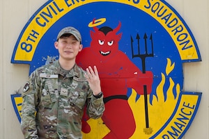 Senior Airman Sam Kim, 8th Civil Engineer Squadron facility maintenance team controller, poses with the 8th CES Red Devil mascot at Kunsan Air Base, Republic of Korea.