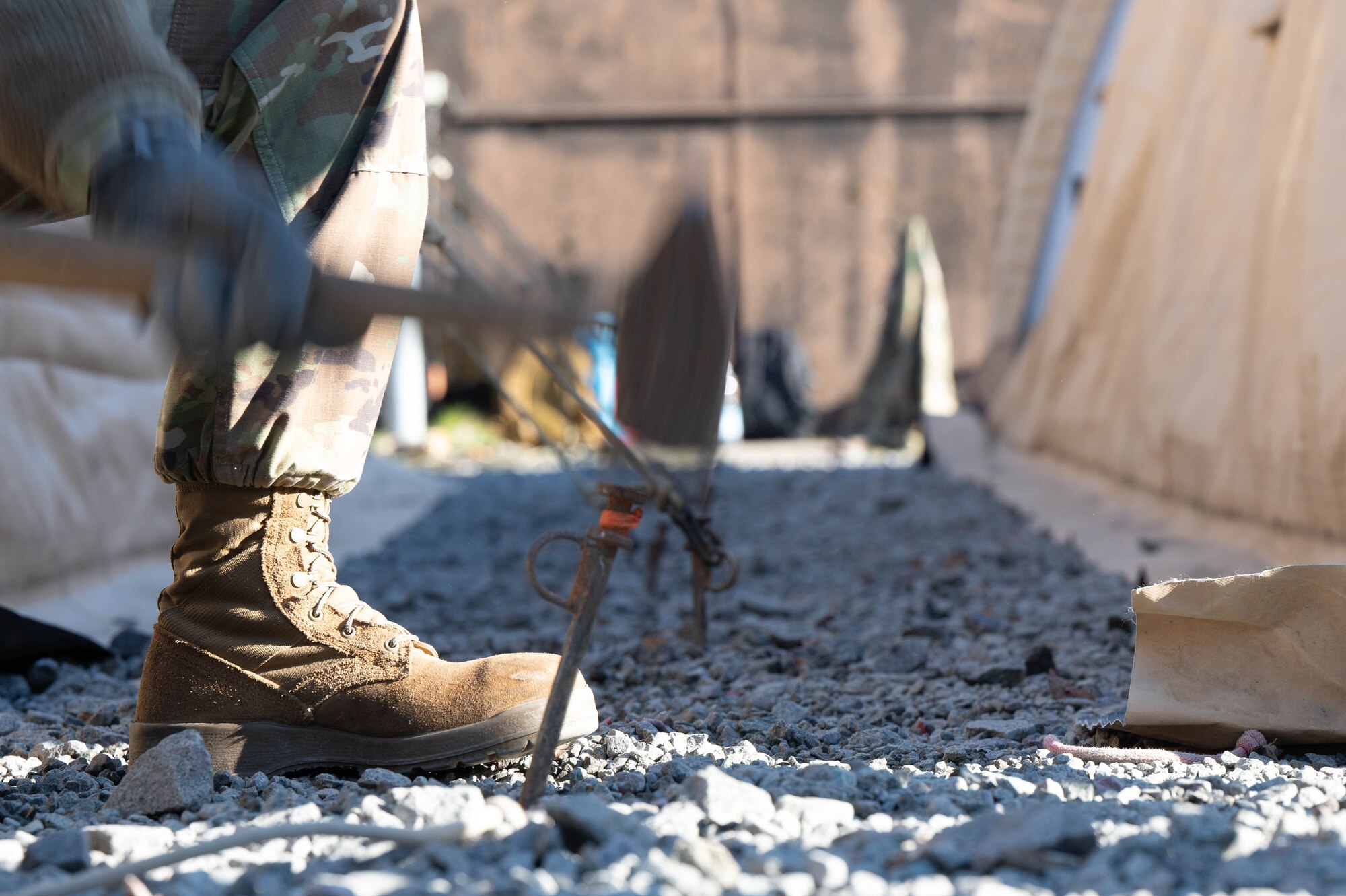 A man uses a sledgehammer to drive a stake into the ground