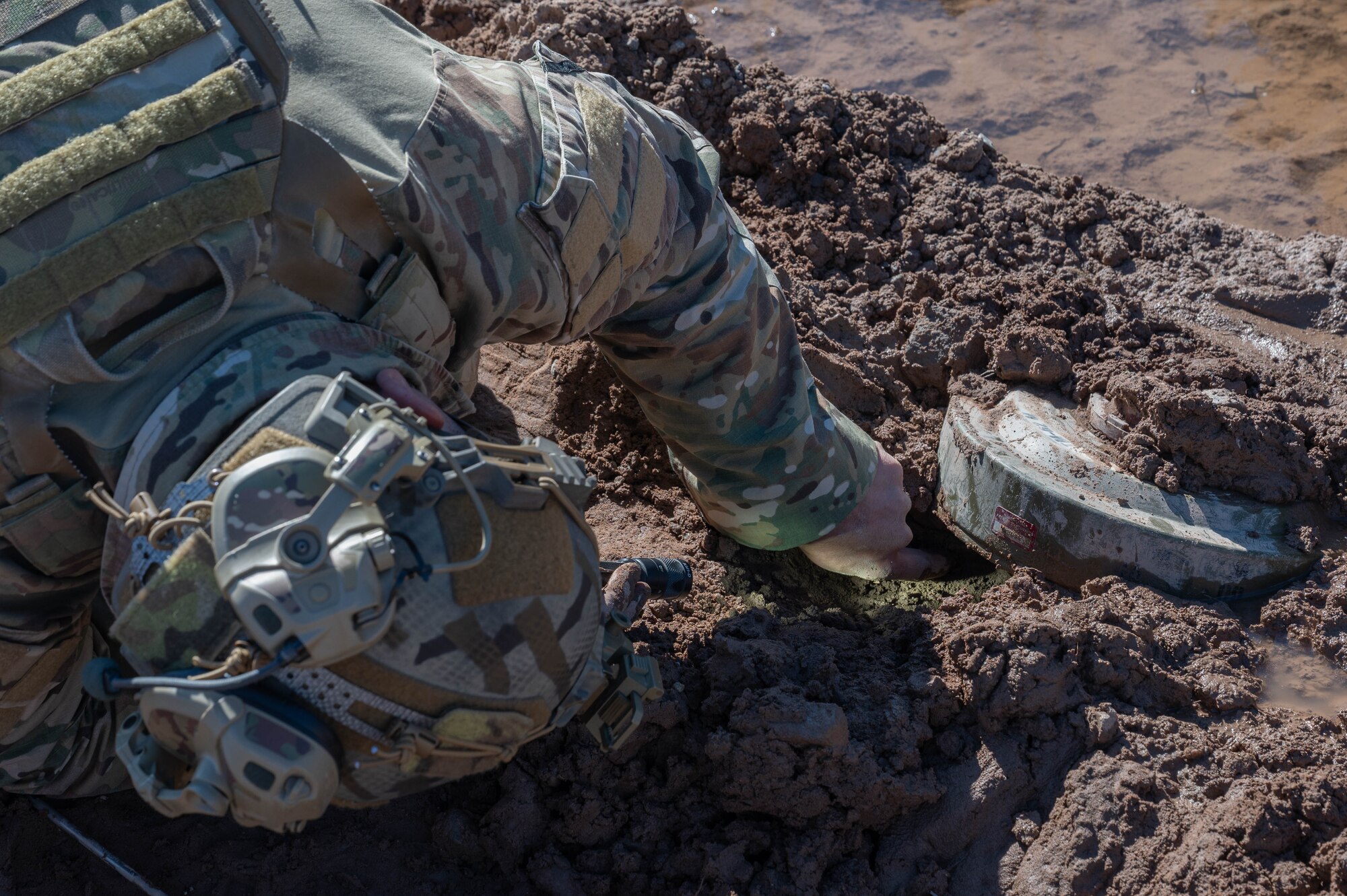 A man inspects the surroundings of a simulated landmine