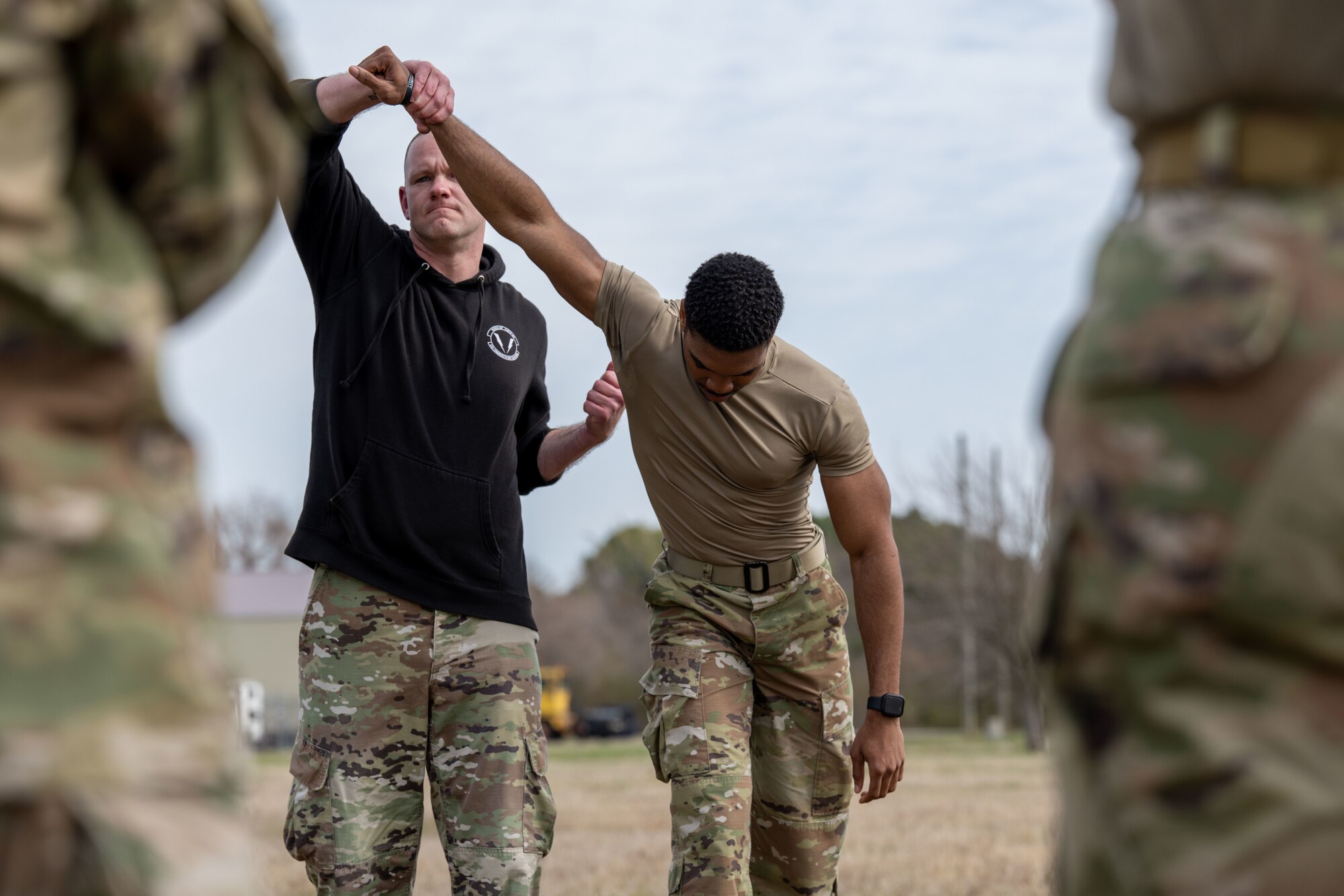 A man holds a student's arm up and preforms a defensive move.