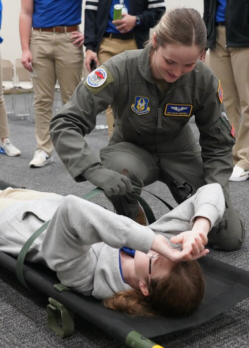 Female Airman straps down a male JROTC cadet to a litter.
