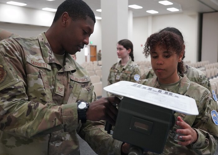 Male Airman shows a female JROTC cadet a TS 45-30A tester.