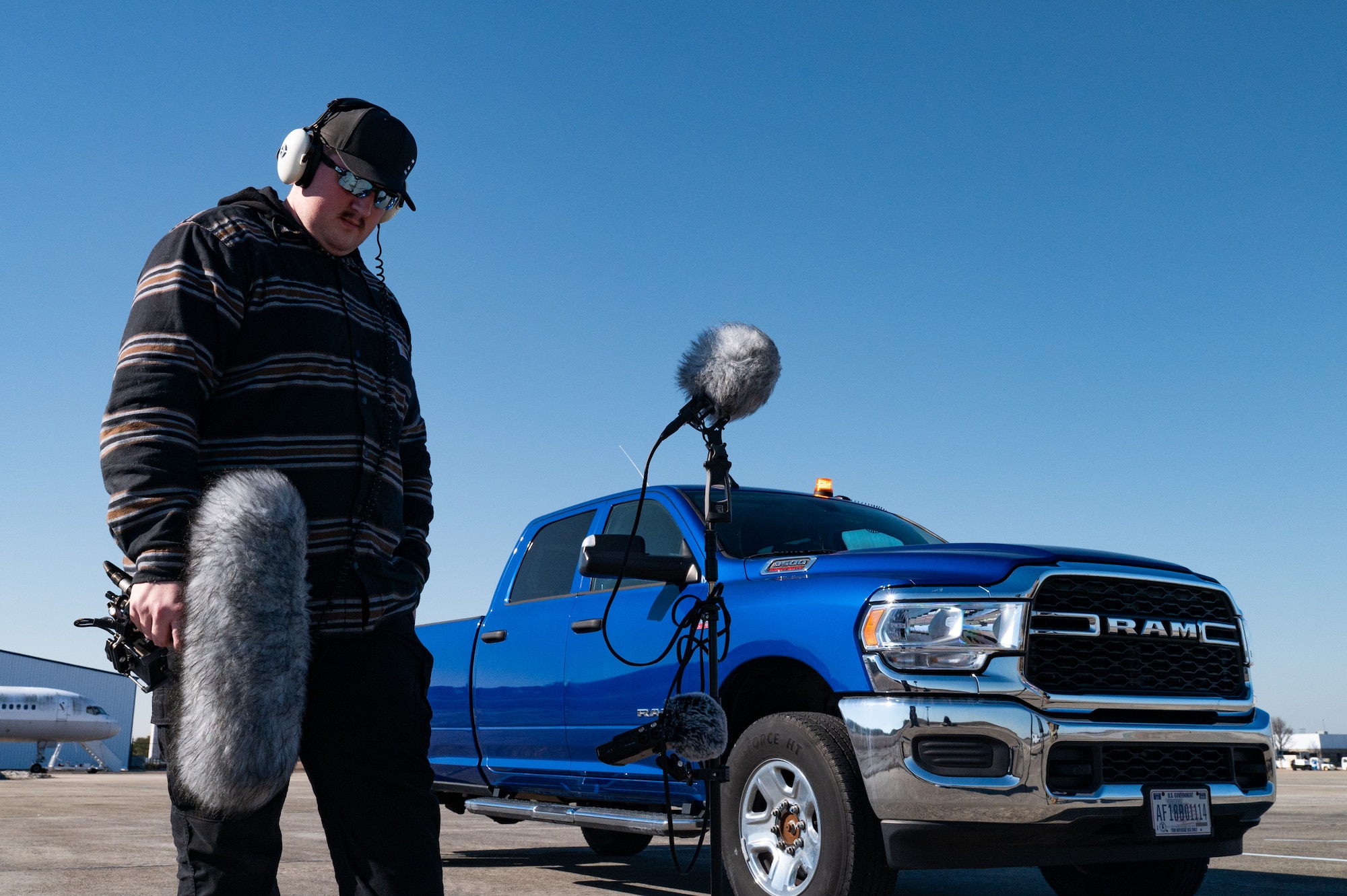 A man stands in front of audio equipment while holding a microphone.