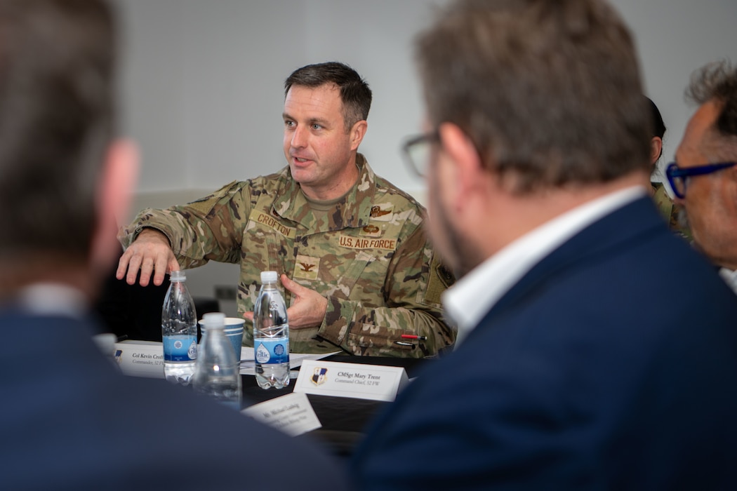 Participants of a host nation forum sit around a table and discuss a mission brief.