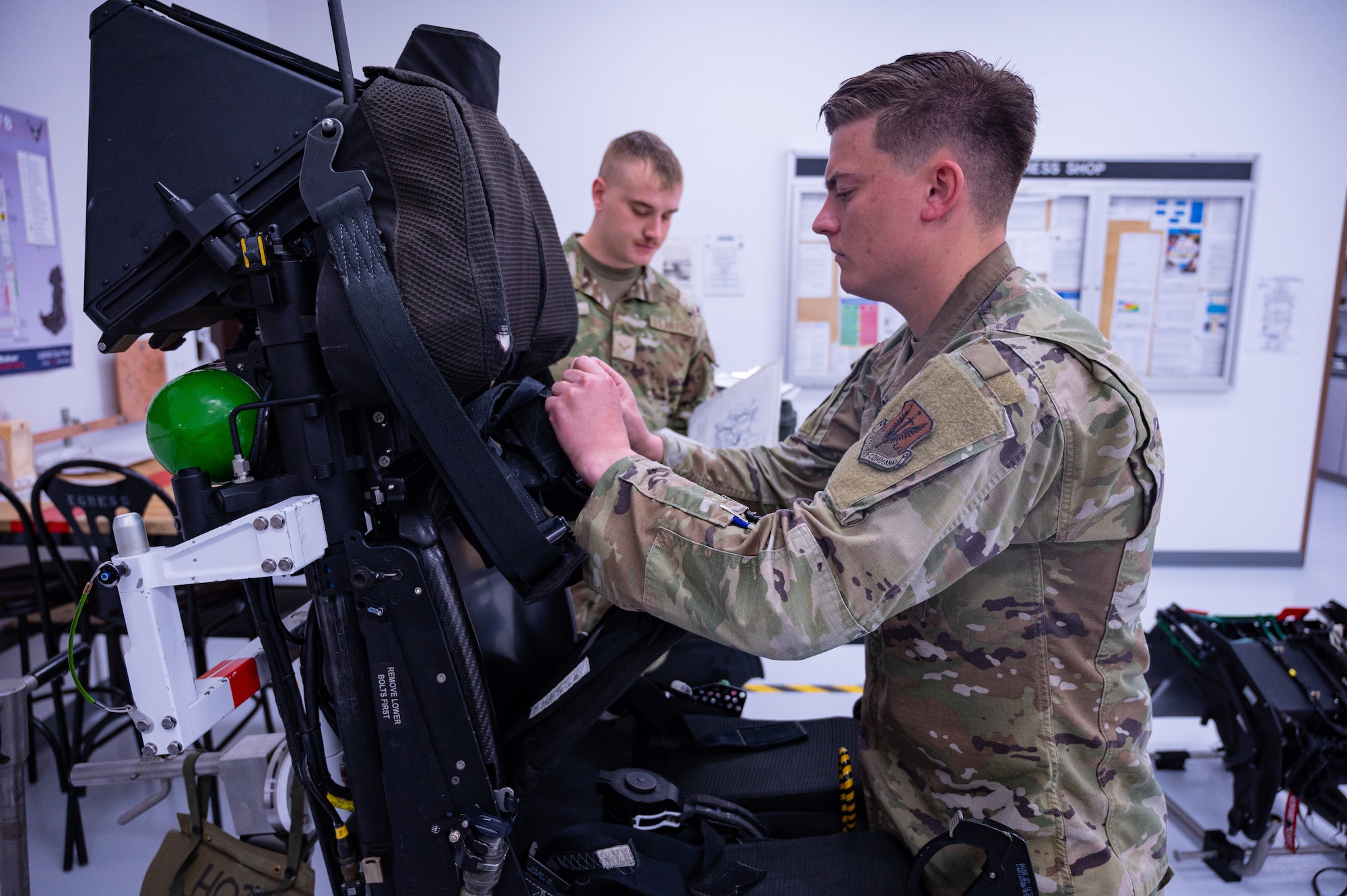 A photo of two Airmen inspecting an ejection seat