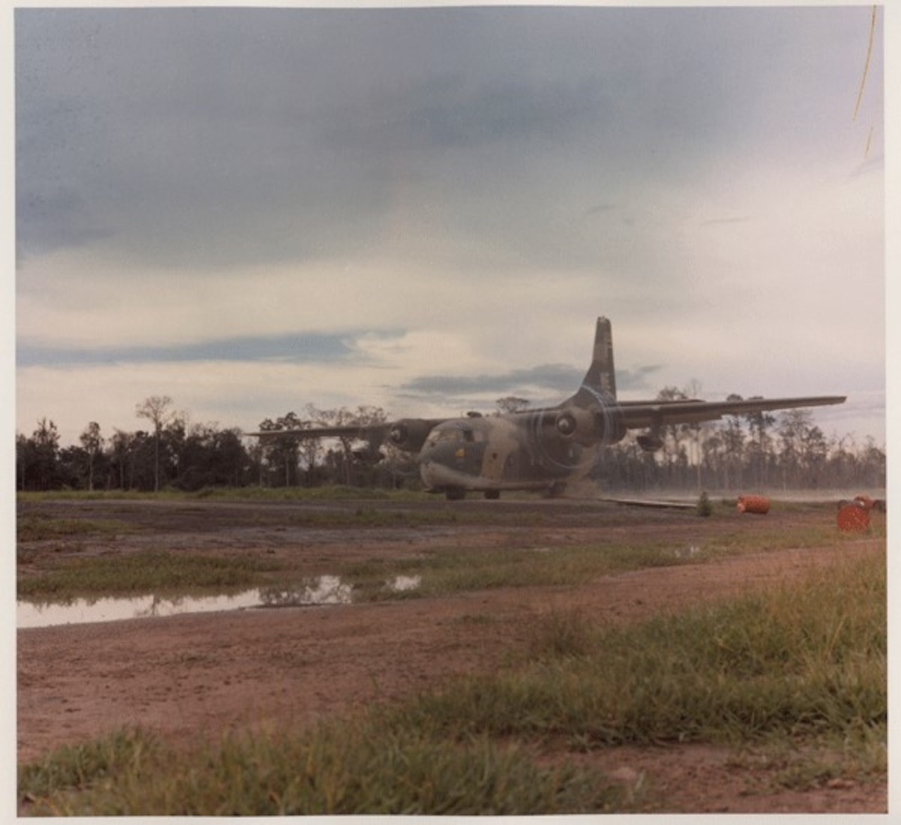 A large military cargo aircraft moves along a dirt airfield.