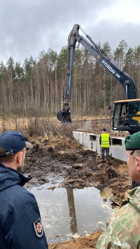 Lithuanian military and law enforcement personnel observe recovery efforts as an excavator gathers soil for a berm March 26 near Pabradė, Lithuania. Lithuanians from across the country’s national and local government have aided U.S. Army Soldiers in the search for four missing U.S. Soldiers from 1st Brigade, 3rd Infantry Division and the recovery efforts of their M88 Hercules armored vehicle found submerged March 26 near the last known location of the Soldiers.