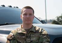 Caucasian Airmen, wearing OCP's, posing in front of a black truck, outside against a blue sky.