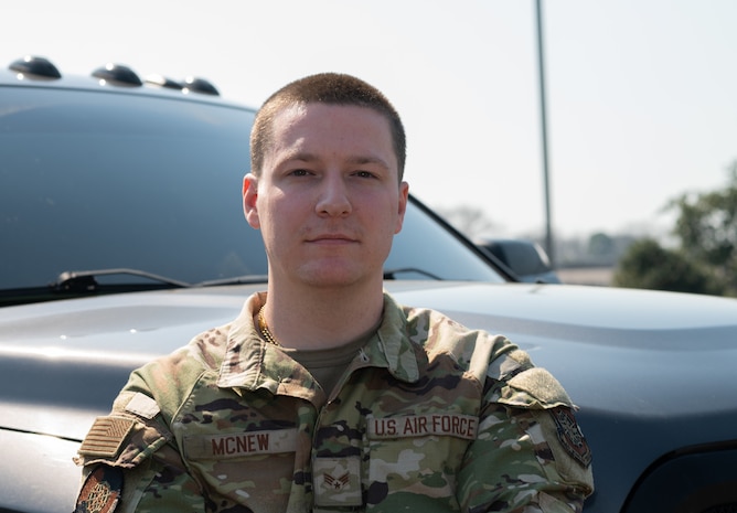 Caucasian Airmen, wearing OCP's, posing in front of a black truck, outside against a blue sky.