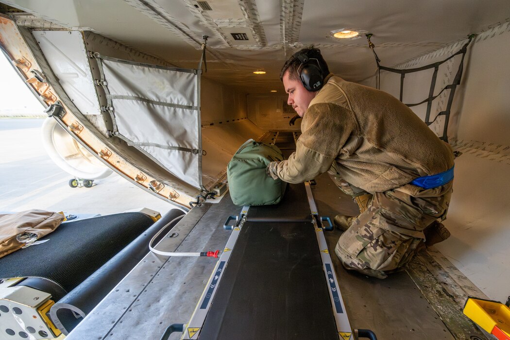 An Airman loads cargo in the cargo area of an airplane