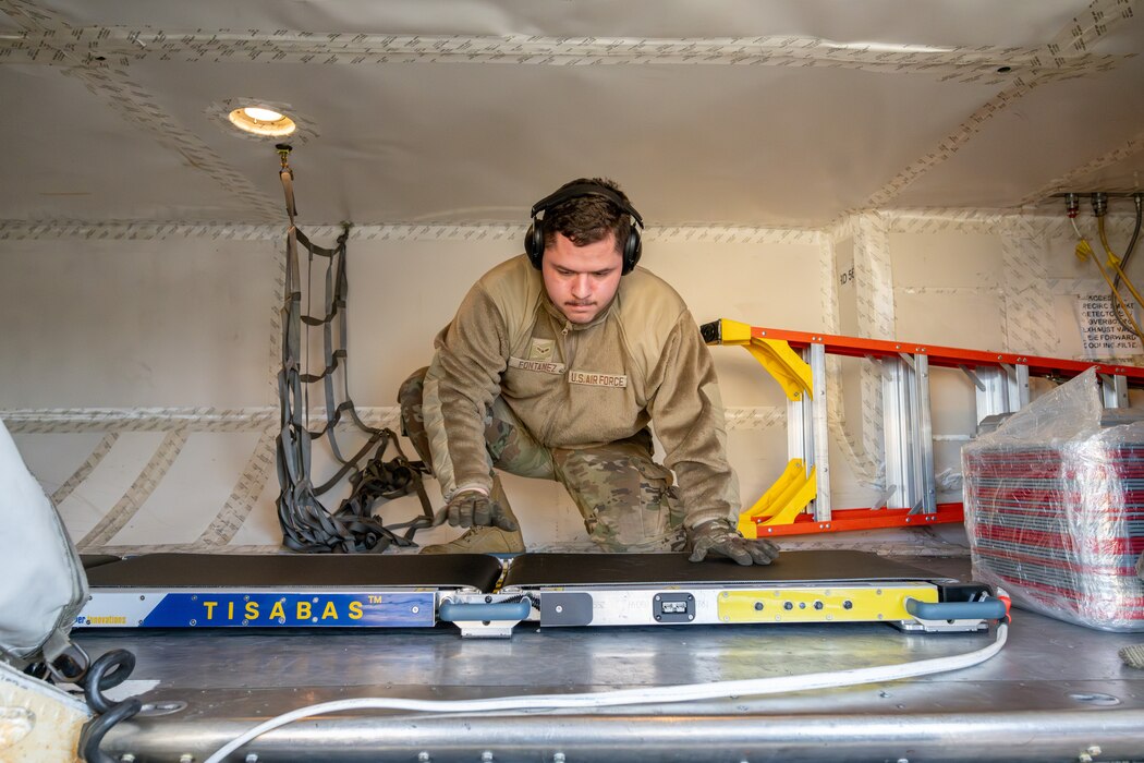 An Airman loads a conveyor belt into the cargo area of an airplane.