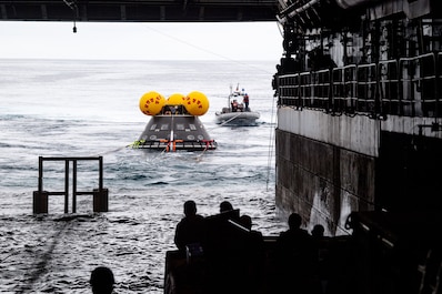 PACIFIC OCEAN (March 26, 2025) — Sailors assigned to amphibious transport dock USS Somerset (LPD 25) and NASA engineers release a crew module test article from the ship’s well deck during NASA Underway Recovery Test 12 in the Pacific Ocean, March 26, 2025. In preparation for NASA's Artemis II crewed mission, which will send four astronauts around the moon and beyond in the Orion spacecraft, NASA and the Department of Defense will conduct a series of tests to demonstrate and evaluate the processes, procedures, and hardware used in recovery operations for crewed lunar missions. The Department of Defense has many unique capabilities that make it an ideal partner to support NASA, including its amphibious ships with the ability to embark helicopters, launch and recover small boats and provide medical care at advanced onboard facilities. (U.S. Navy photo by Mass Communication Specialist 2nd Class Evan Diaz)