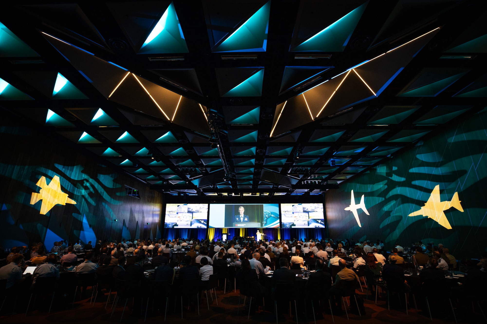 A Large room with an audience facing a distant stage.
