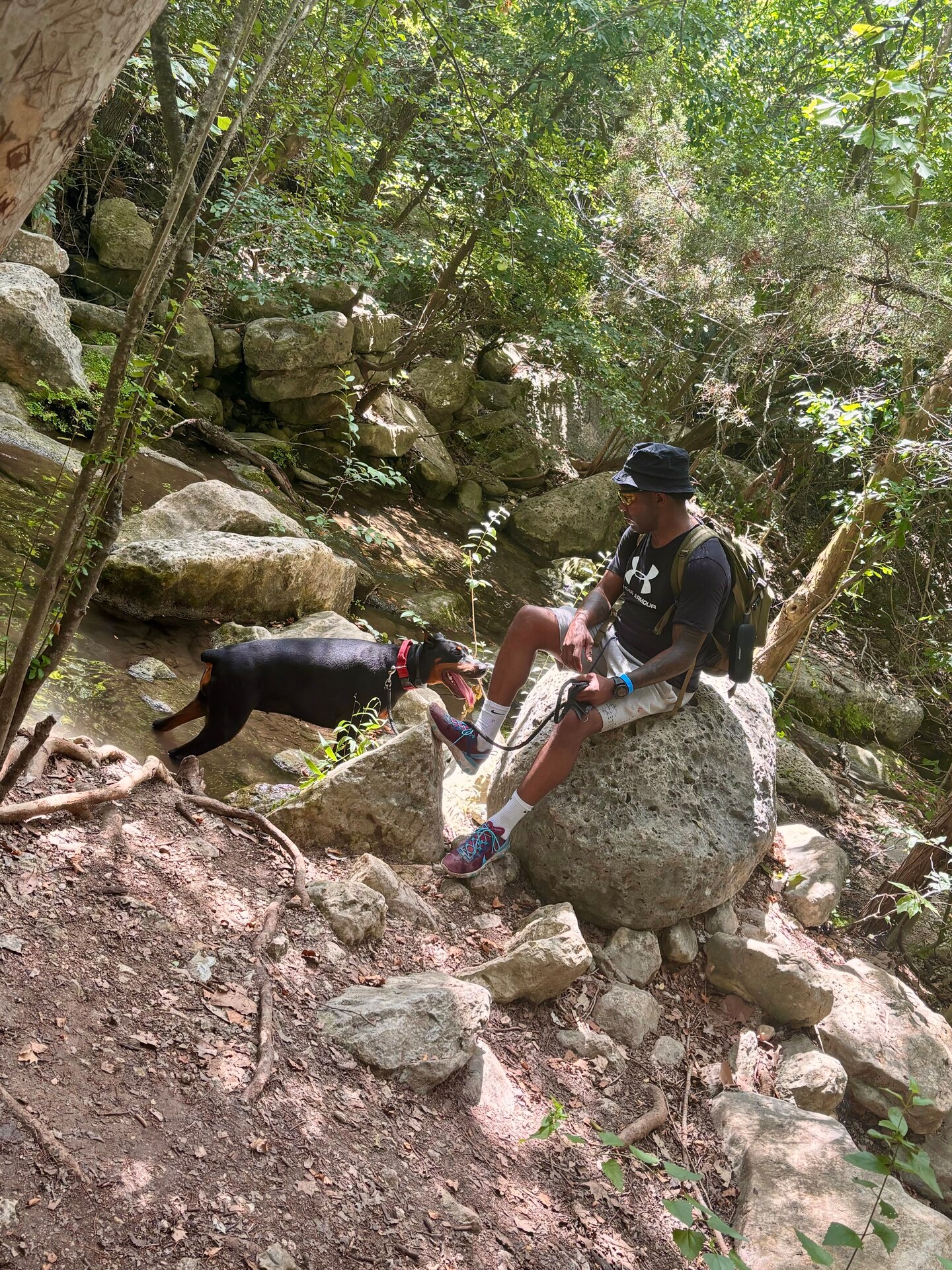 Man in hiking gear poses with pet dog in nature.