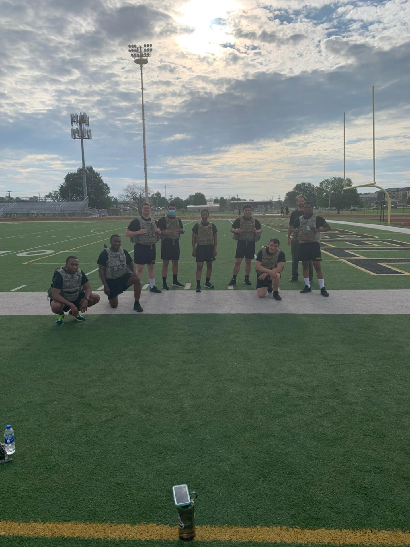 Group of U.S. Army Soldiers in PT uniform pose together on a football field.