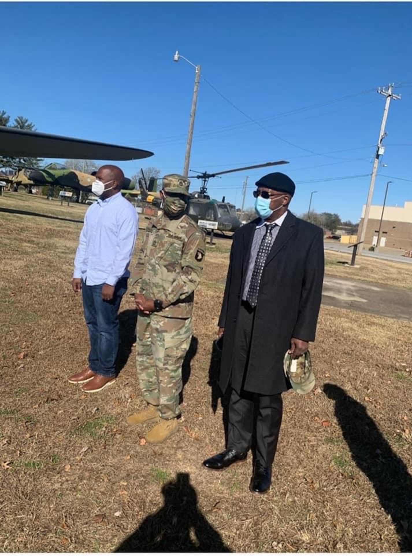 Male U.S. Army Soldier in uniform stands with father and brother in civilian attire during promotion ceremony