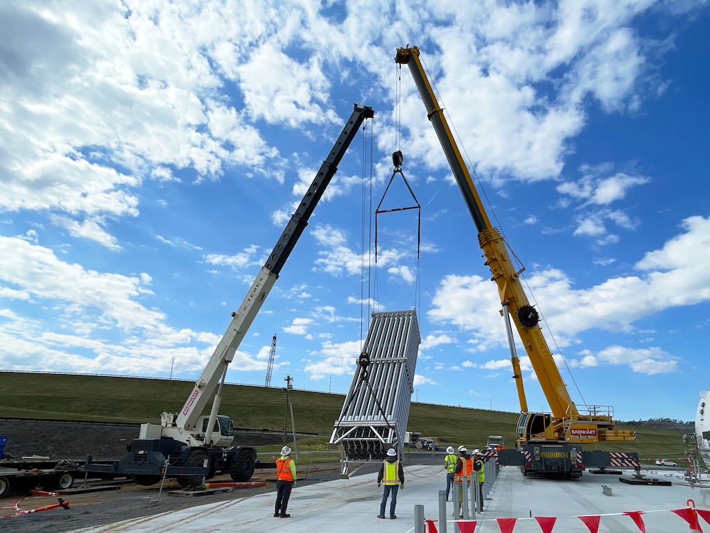 Two cranes position one of eight 34.5-foot-tall vaporizers into place at the new Wolf Creek Dam cryogenic facility in Jamestown, Kentucky on March 26, 2025. This system will allow the U.S. Army Corps of Engineers to diffuse oxygen into the upstream Cumberland reservoir, boosting hydropower efficiency.