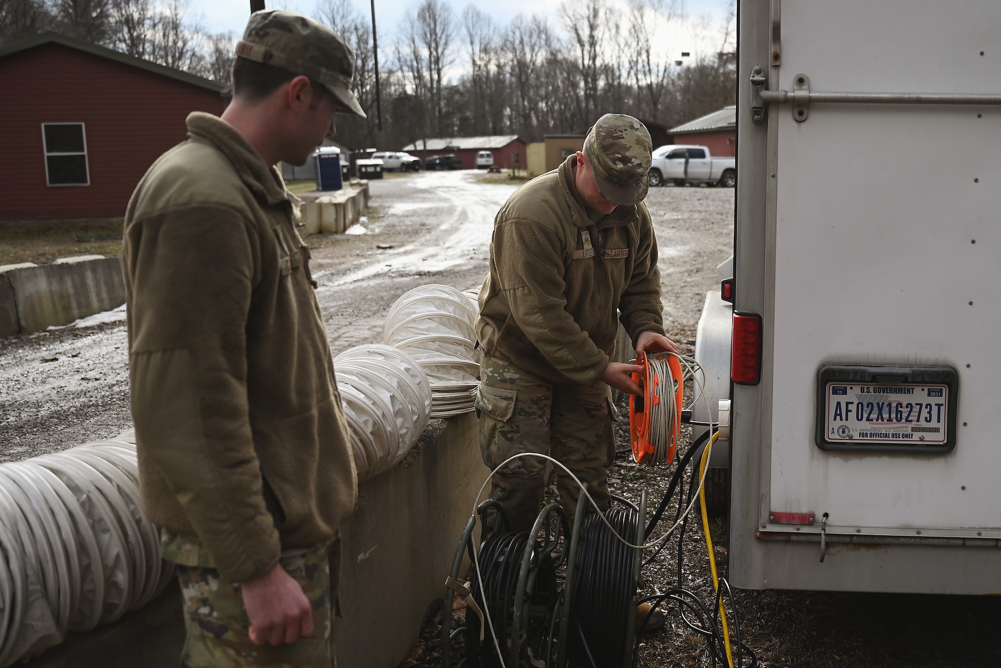 U.S. Air Force Staff Sgt. Noah Little, a communications specialist assigned to the 178th Wing, Ohio Air National Guard, feeds communications cables into the Joint Incident Site Communications terminal Feb. 2, 2025 as a junior enlisted airman observes during annual training at Camp Holland in Butlerville, Indiana. The training focused on building foundational skills that enable them to operate in a contested, degraded, and operationally limited environment with minimal support.. (U.S. Air National Guard photo by Shane Hughes)