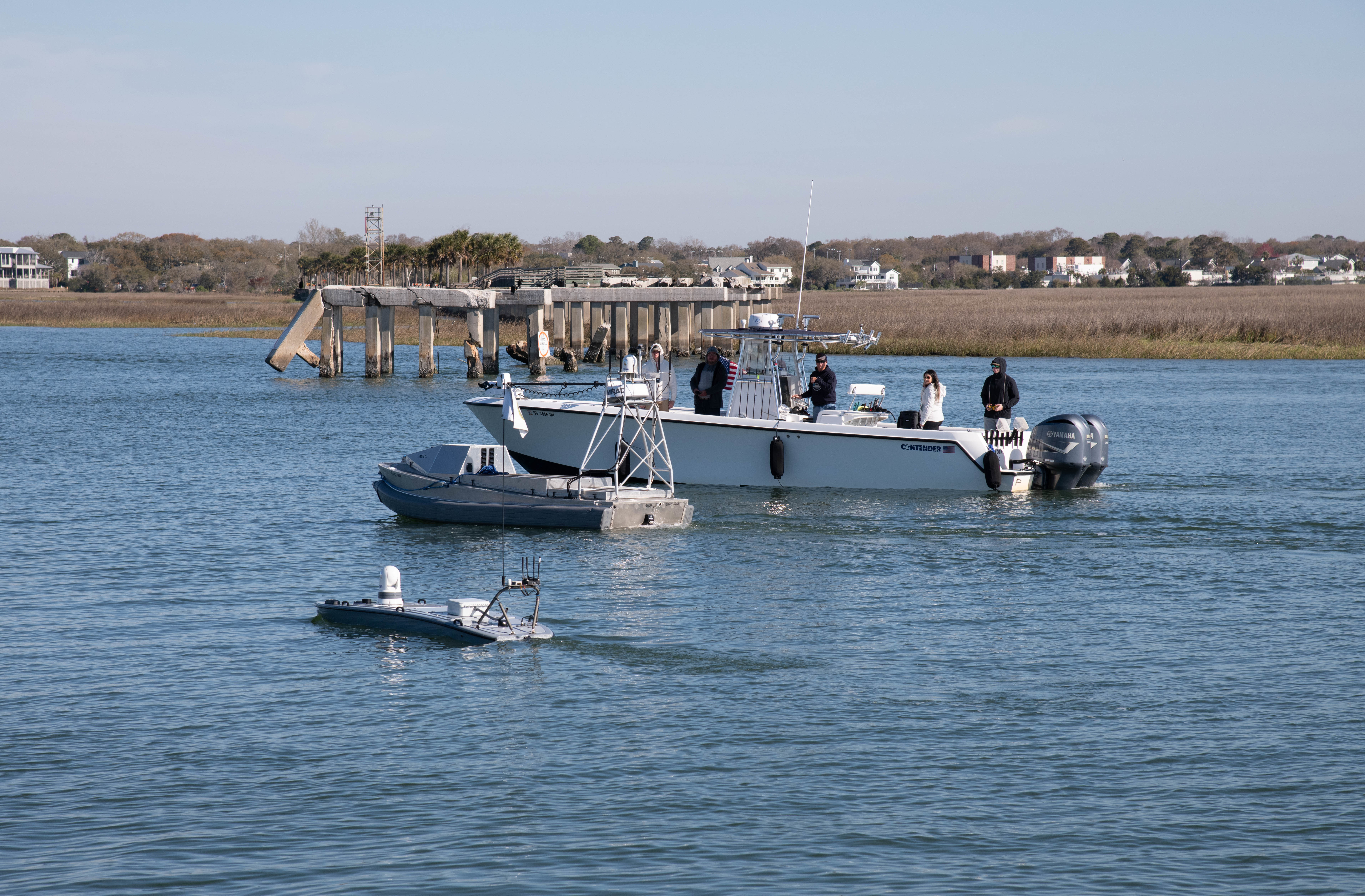 A boat in the water with unmanned autonomous vehicle operators overseeing two unmanned autonomous vehicles.