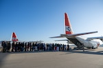 A line of illegal aliens is seen waiting to board a Coast Guard C-130 Hercules aircraft.