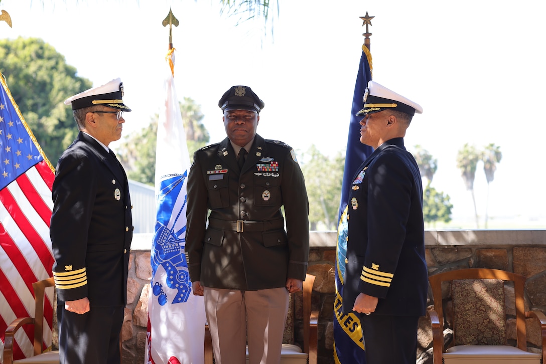 Three people stand in formation during a ceremony.