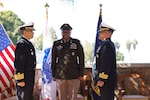 Three people stand in formation during a ceremony.
