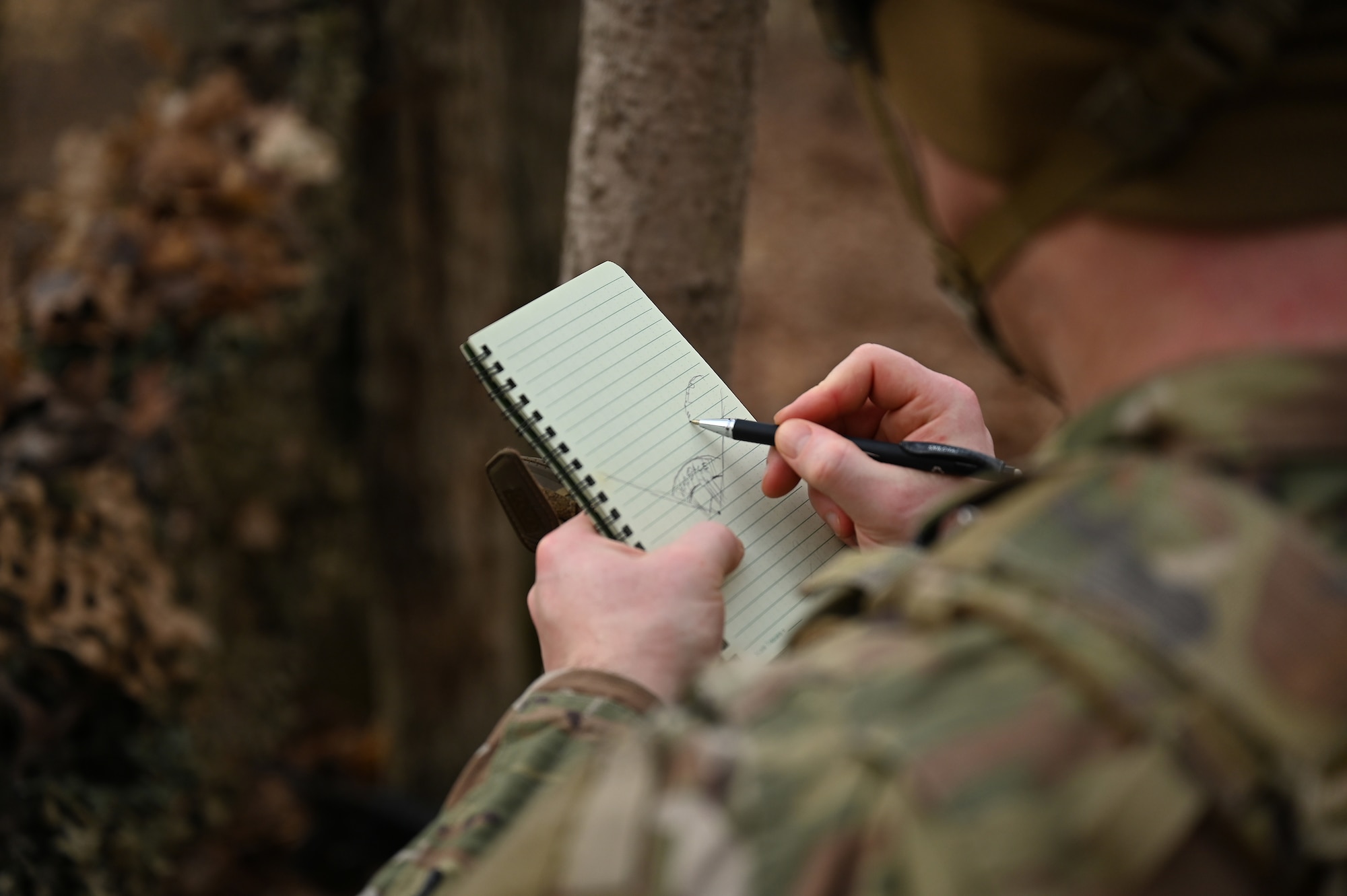 A U.S. Airman assigned to the 178th Security Forces Squadron, Ohio Air National Guard draws terrain visible from his defensive fighting position on a range card Feb. 4, 2025 during annual training at Camp Holland in Butlerville, Indiana. The training, primarily focused on mission planning, included attacking and defending positions and aligning tactics with the Air Force doctrine of Agile Combat Employment. (U.S. Air National Guard photo by Shane Hughes)