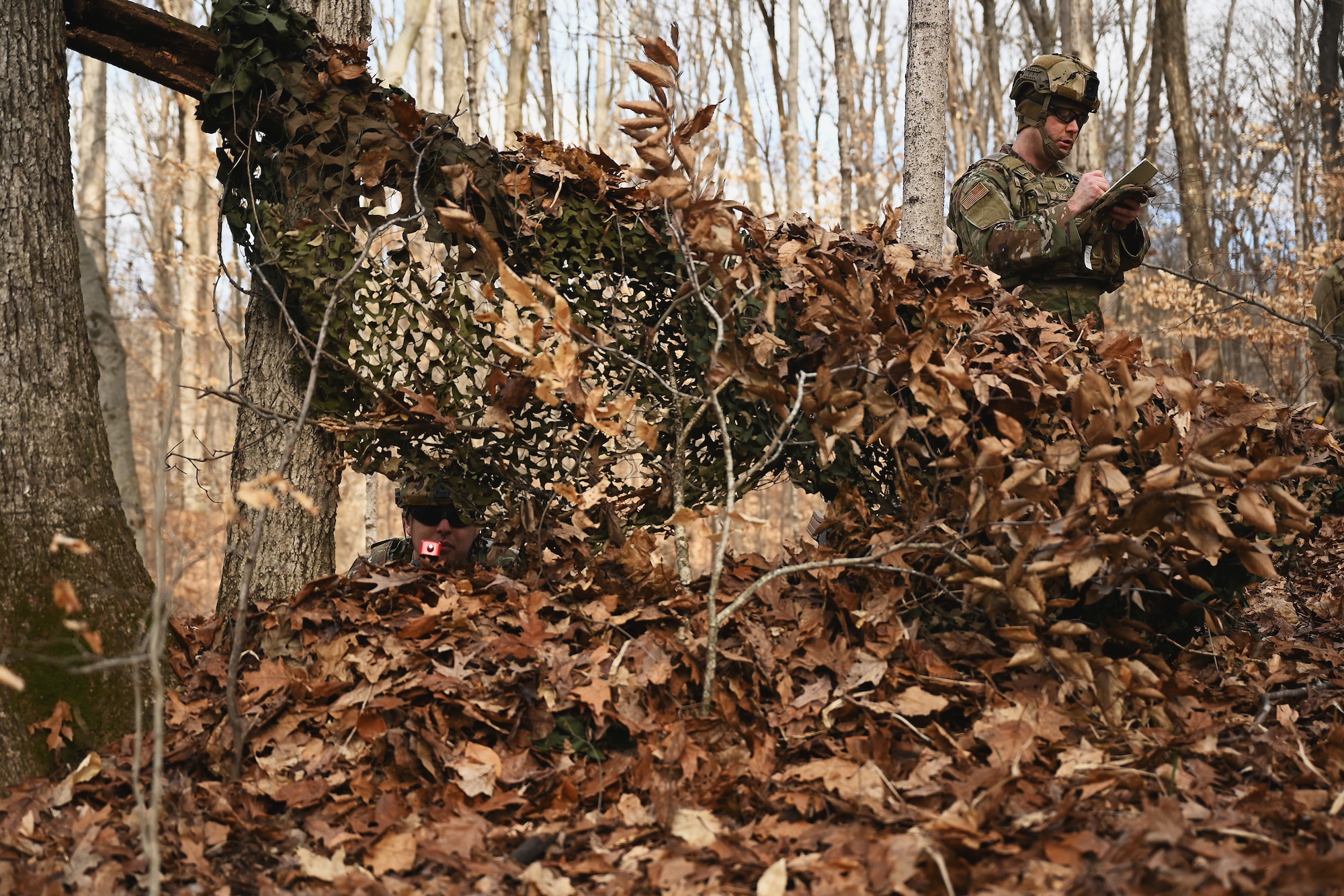 U.S. Airmen assigned to the 178th Security Forces Squadron, Ohio Air National Guard scan the woods for potential threats after locating their mission objective and building their defensive fighting positions Feb. 4, 2025 during annual training at Camp Holland in Butlerville, Indiana. The training, primarily focused on mission planning, included attacking and defending positions and aligning tactics with the Air Force doctrine of Agile Combat Employment. (U.S. Air National Guard photo by Shane Hughes)