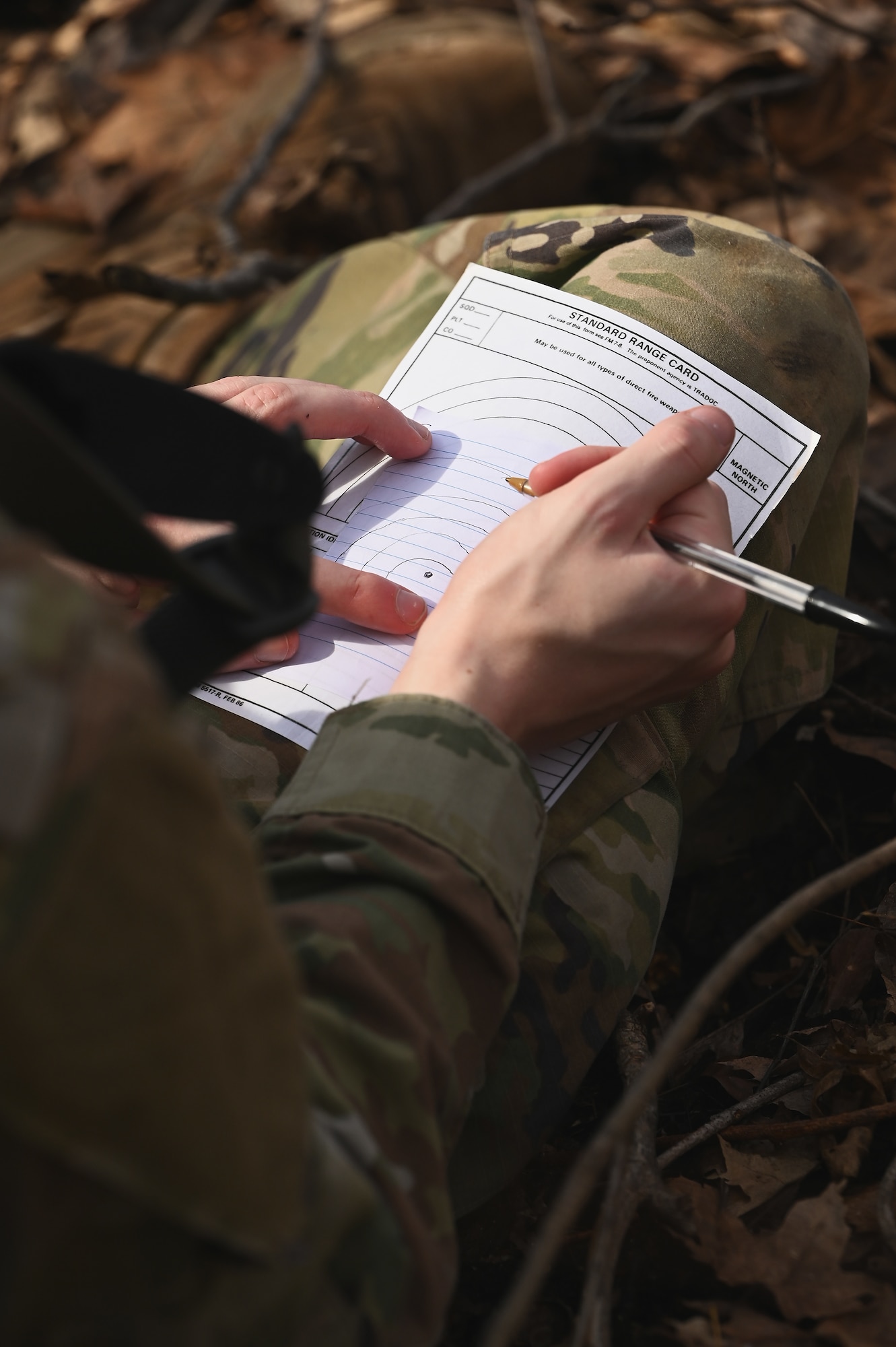 A  U.S. Airman assigned to the 178th Security Forces Squadron, Ohio Air National Guard draws terrain visible from his defensive fighting position on a range card Feb. 3, 2025 during annual training at Camp Holland in Butlerville, Indiana. The training, primarily focused on mission planning, included attacking and defending positions and aligning tactics with the Air Force doctrine of Agile Combat Employment. (U.S. Air National Guard photo by Shane Hughes)