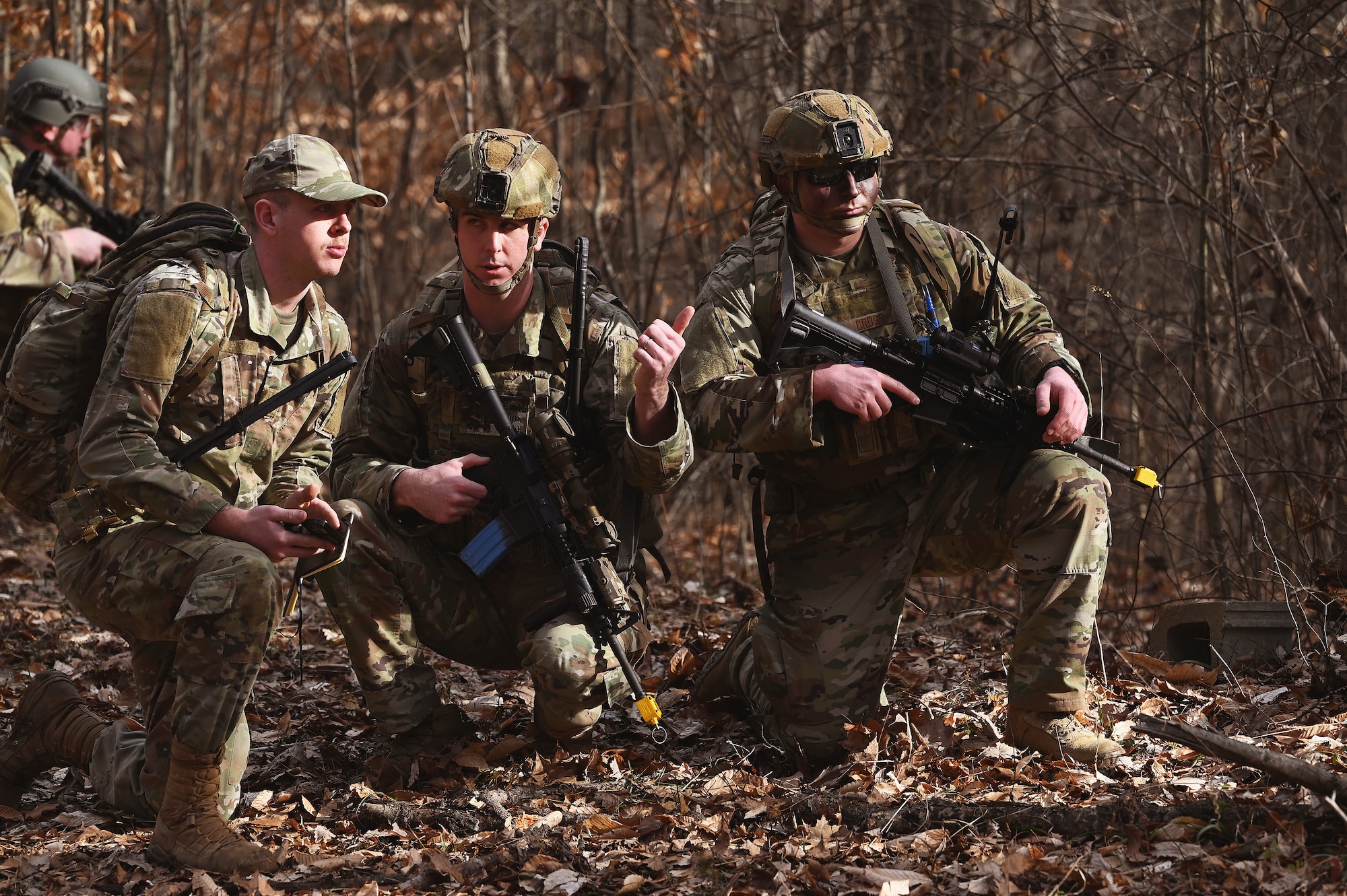 U.S. Airmen assigned to the 178th Security Forces Squadron, Ohio Air National Guard scan the woods for potential threats and discuss potential routes to their mission objective Feb. 3, 2025 during annual training at Camp Holland in Butlerville, Indiana. The training focused on empowering subordinates at the lowest capable level to make decisions and take decisive action at their level and providing the flexibility and agility required to seize opportunities despite enemy denial or degradation of communications. (U.S. Air National Guard photo by Shane Hughes)