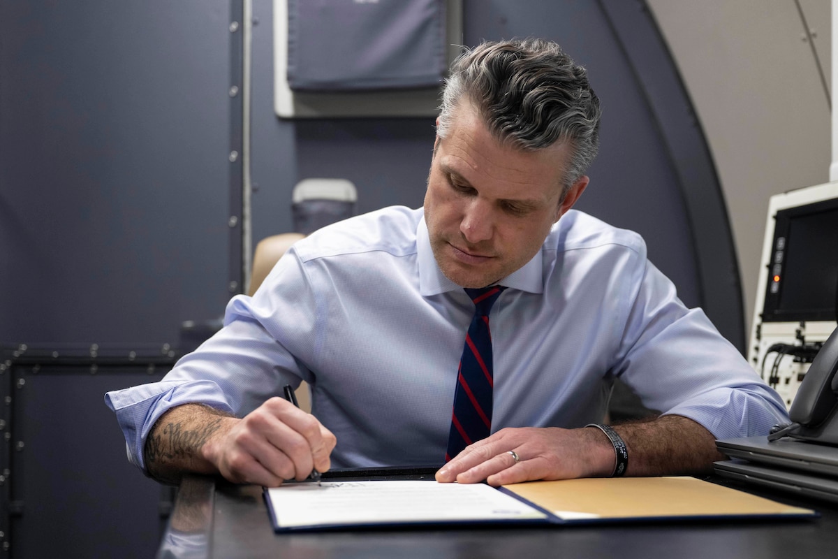 A man is sitting at a desk signing a document.