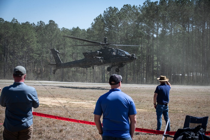 Three engineers oversee an Apache helicopter covering.