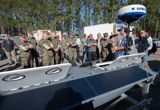 Engineers speaking to a group of Marines in uniforms about the autonomous system equipment.