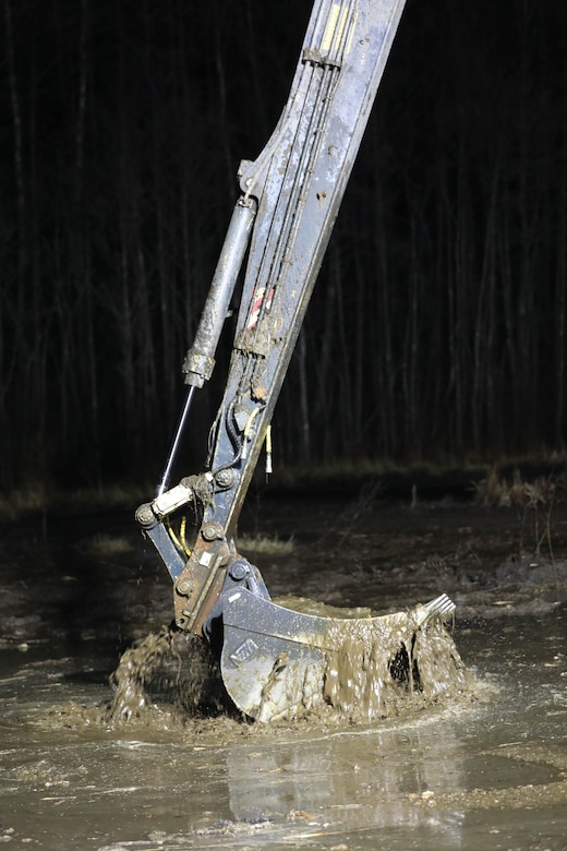 An excavator removes silt and debris as Lithuanian Armed Forces personnel and emergency services work through the night  during recovery efforts for a U.S. Army M88 Hercules recovery vehicle submerged under several meters of water in a swamp near a training area in Pabradė, Lithuania, March 28, 2025.  (U.S. Army photo by Staff Sgt. Rose Di Trolio)
